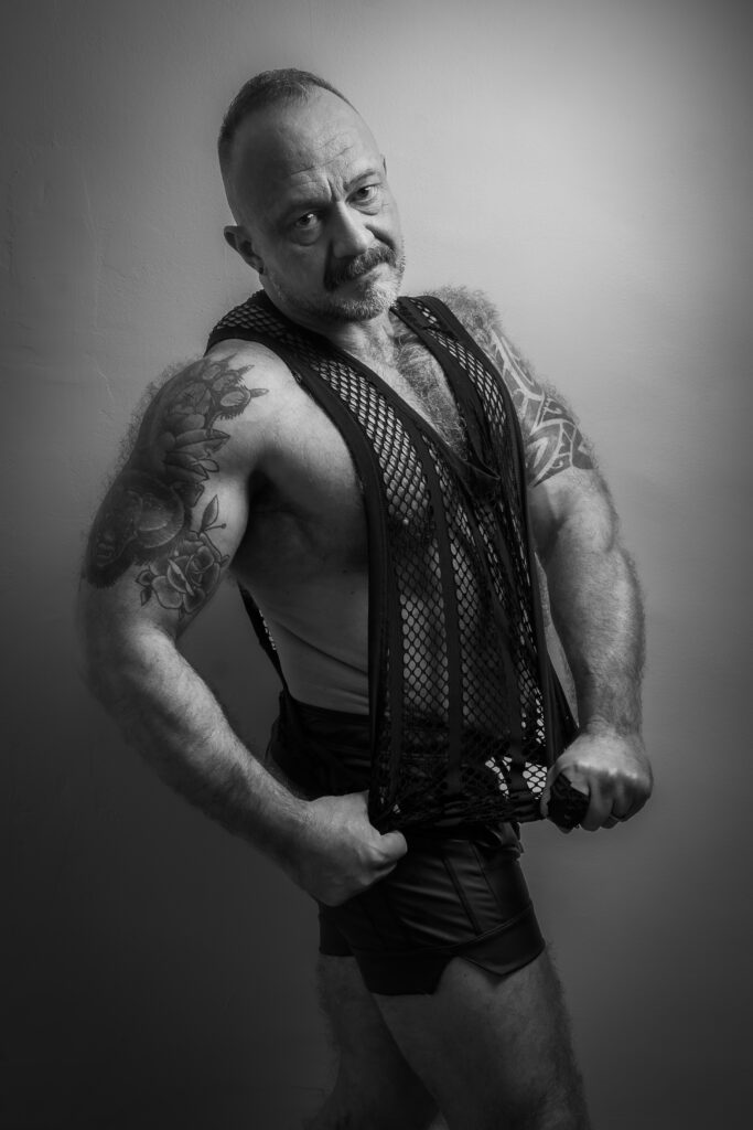 Retrato de Andy en blanco y negro, con mirada directa y chaleco de malla